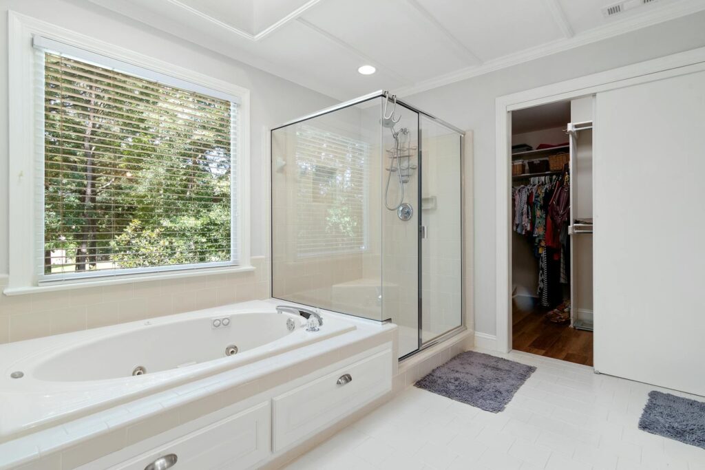 Spacious bathroom featuring a bathtub, glass shower, and walk-in closet.