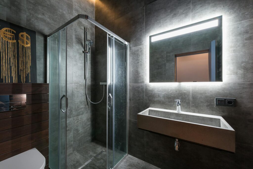 Contemporary bathroom featuring a minimalist design with a glass shower and illuminated mirror.